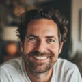 Homme souriant avec barbe, ambiance chaleureuse.
